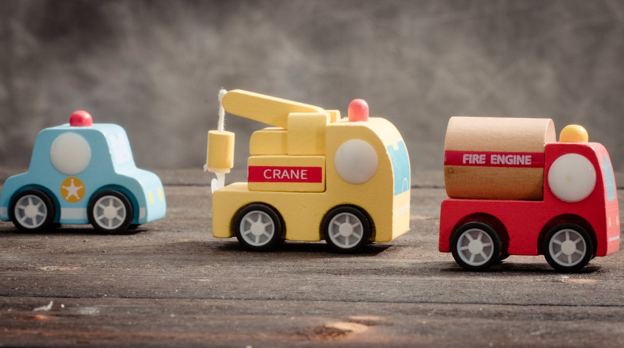 Colorful wooden toy vehicles on a wooden table with a soft-focus background.